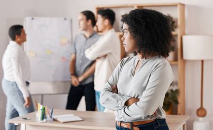Woman annoyed while men collaborate behind her - Hostile Work Environment